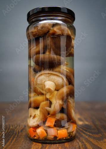 Pickled mushrooms in a glass jar . Salted homemade mushrooms . Rustic food . photo