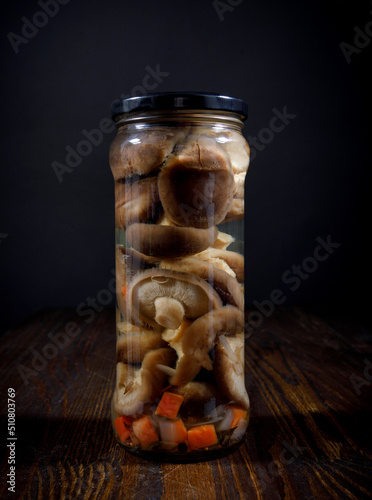 Pickled mushrooms with vegetables in a glass jar . Salted homemade mushrooms . Rustic food . photo