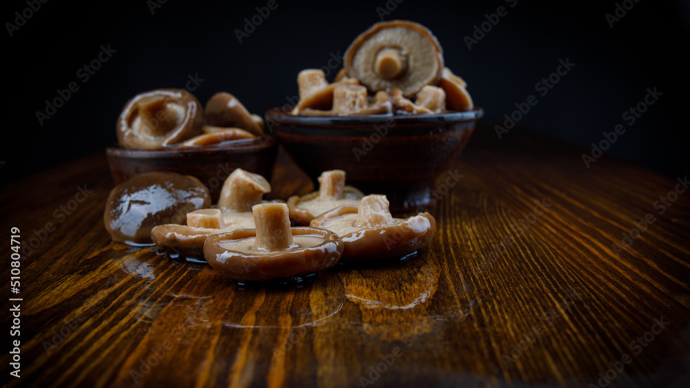 Black milk mushrooms on a wooden table . Beautiful pickled mushrooms . Black milk mushrooms on a wooden table . Beautiful pickled mushrooms .