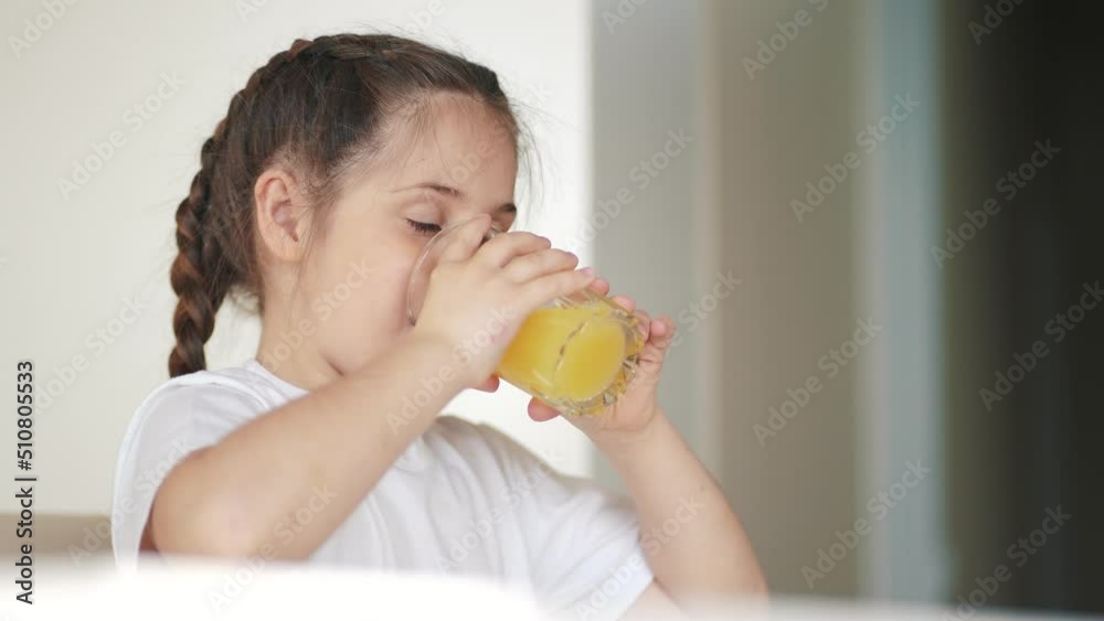 girl child drinking juice. happy family a indoors healthy eating kid dream concept. daughter girl drinking yellow juice from a glass cup in the kitchen. child drinking fruit juice girl child drinking juice. happy family a indoors healthy eating kid dream concept. daughter girl drinking yellow juice from a glass cup in the kitchen. child drinking fruit juice
