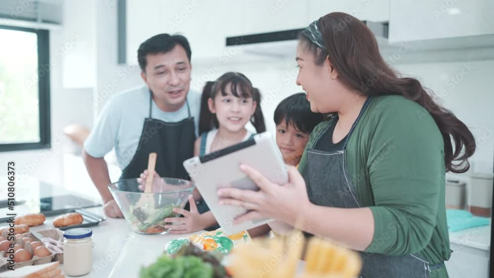 family person using digital tablet to learning to cooking a food in kitchen, child daughter with mother and father lifestyle at home together, fresh vegetable salad and meal for learn to making menu family person using digital tablet to learning to cooking a food in kitchen, child daughter with mother and father lifestyle at home together, fresh vegetable salad and meal for learn to making menu