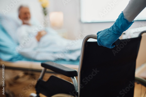 Leinwand Poster Close up of nurse pushing wheelchair in hospital ward.