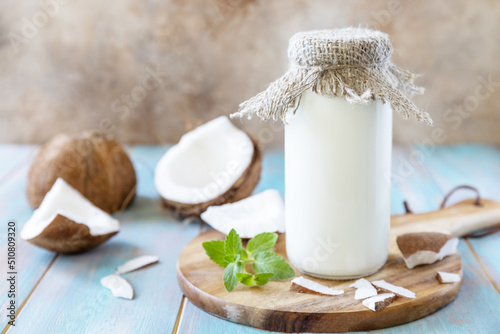 Vegan non dairy alternative milk, health content. Organic coconut milk in a bottle on a rustic table. photo