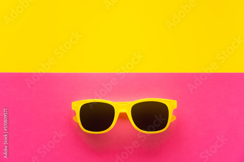 Top view of sunglasses on yellow and pink background.