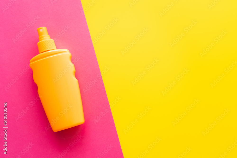 Top view of sunblock on pink and yellow background.