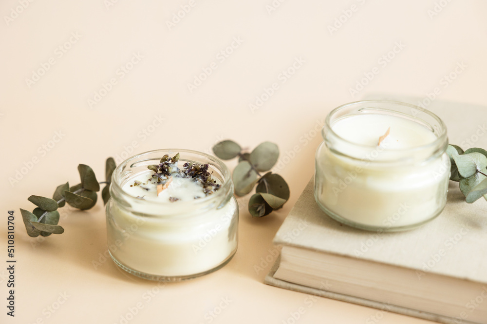 Two candmade candles from paraffin and soy wax in glass with wooden wick and dry herbal isolated on pastel beige background. Flat lay, top view, copy space Two candmade candles from paraffin and soy wax in glass with wooden wick and dry herbal isolated on pastel beige background. Flat lay, top view, copy space
