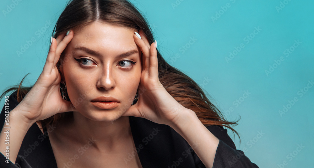 Young woman massages her face on a blue background. Close-up.