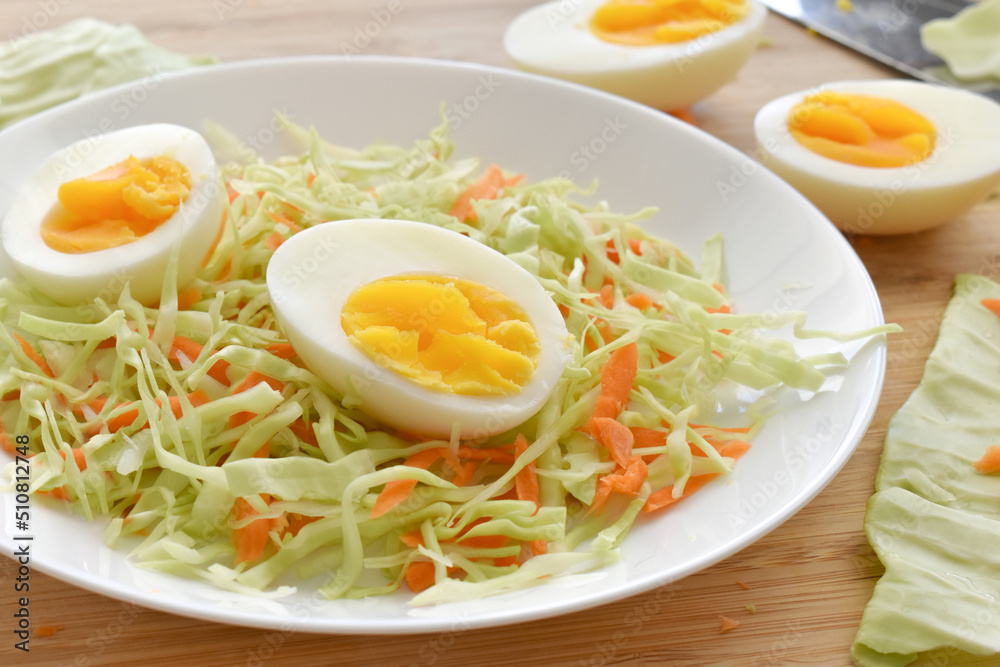 Boiled egg salad with cabbage and carrot. Coleslaw with boiled on a white plate. Boiled egg salad with cabbage and carrot. Coleslaw with boiled on a white plate.