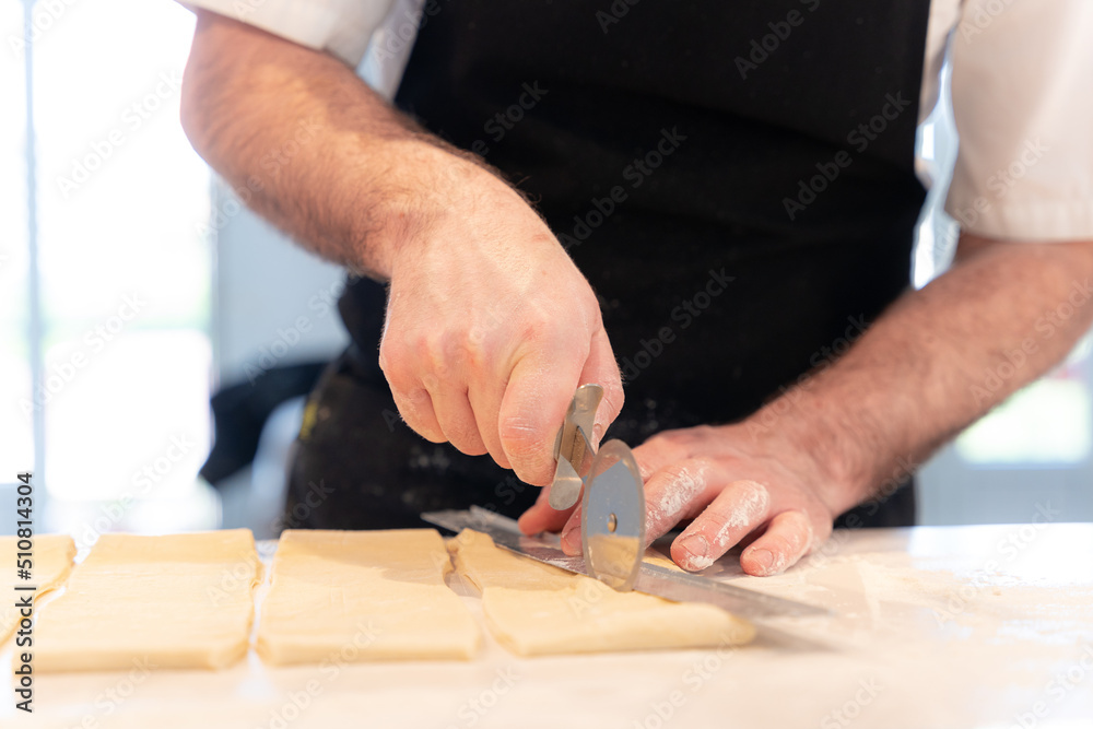 Detail of the hands of a man cooking croissants, measuring the puff pastry and making cuts, work at home Detail of the hands of a man cooking croissants, measuring the puff pastry and making cuts, work at home