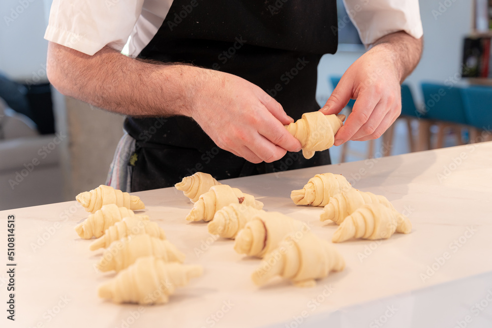 Hands of a man cooking small croissants at home, finishing handling them Hands of a man cooking small croissants at home, finishing handling them