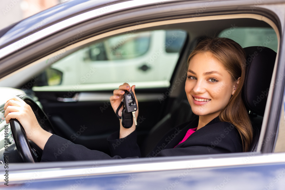 Young woman showing the key of new car