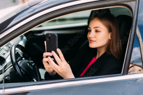 Young woman using cellphone to take photo inside a car