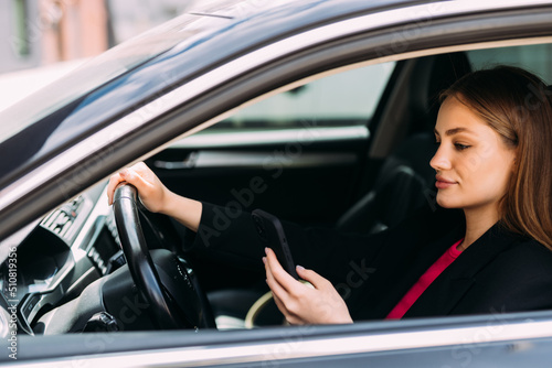 Business woman sitting in car and using her smartphone. © F8  \ Suport Ukraine