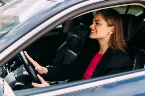 Young woman hand pressing the horn button while driving a car through the road.