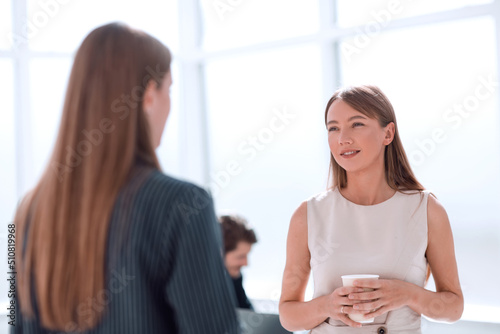 businesswoman with a glass of coffee discussing something with her colleague