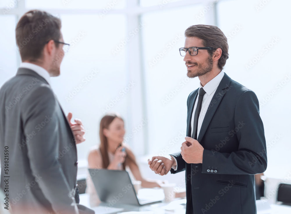 businessman explaining something to his colleague standing in the office. businessman explaining something to his colleague standing in the office.