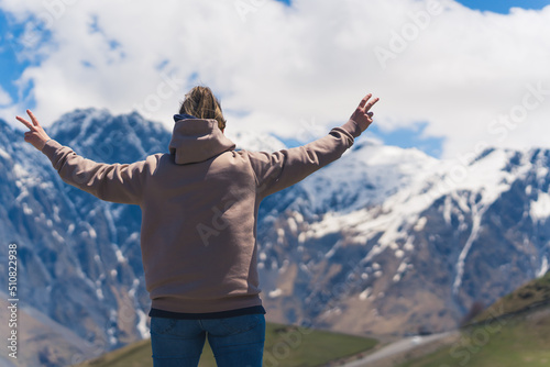 young woman enjoying the view of the Caucasus mountains in Kazbegi, Georgia. majestic Caucasus mountains and Gergeti Trinity Church. High quality photo