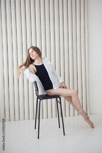Girl in a white shirt sits on a chair