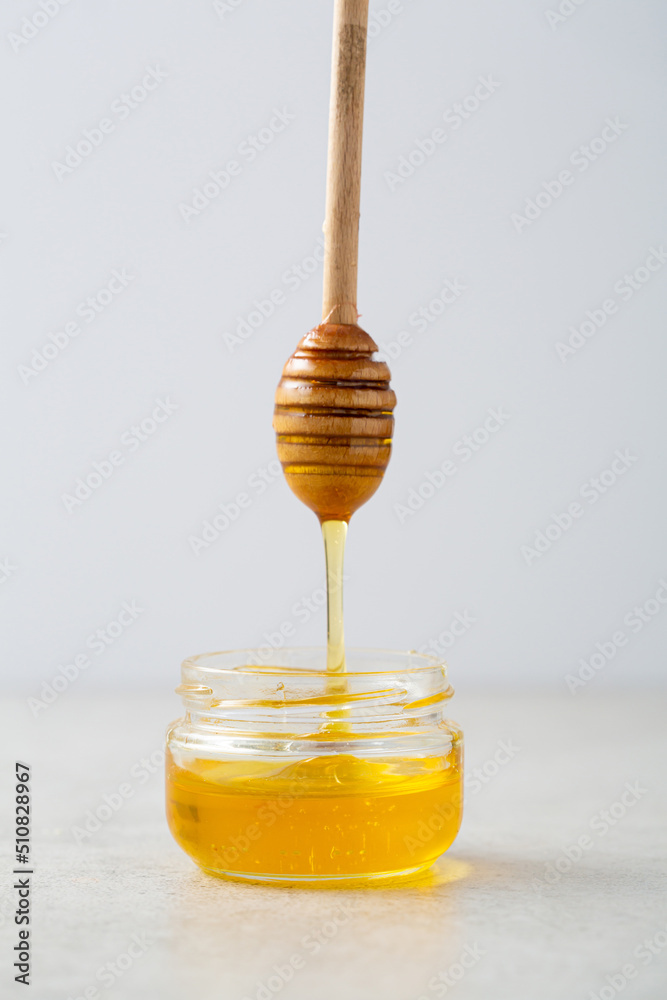 Golden honey in glass jar with pouring honey wooden spoon copy space food Golden honey in glass jar with pouring honey wooden spoon copy space food