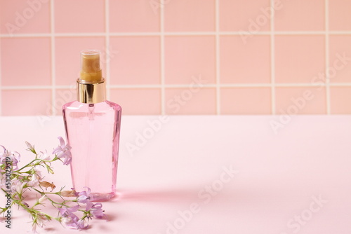 Pink perfume cosmetic bottle and natural flowers