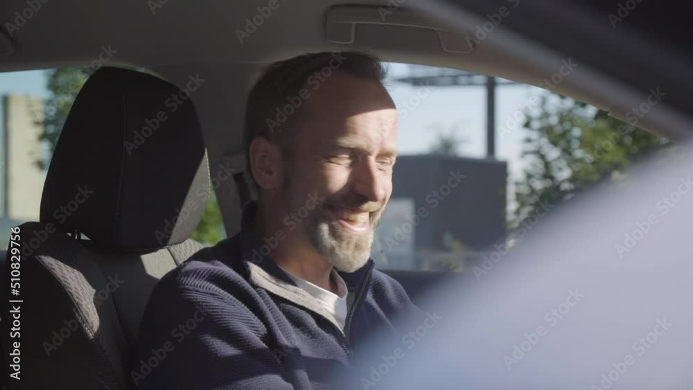 A middle-aged handsome Caucasian man laughs at the camera in a car - closeup A middle-aged handsome Caucasian man laughs at the camera in a car - closeup