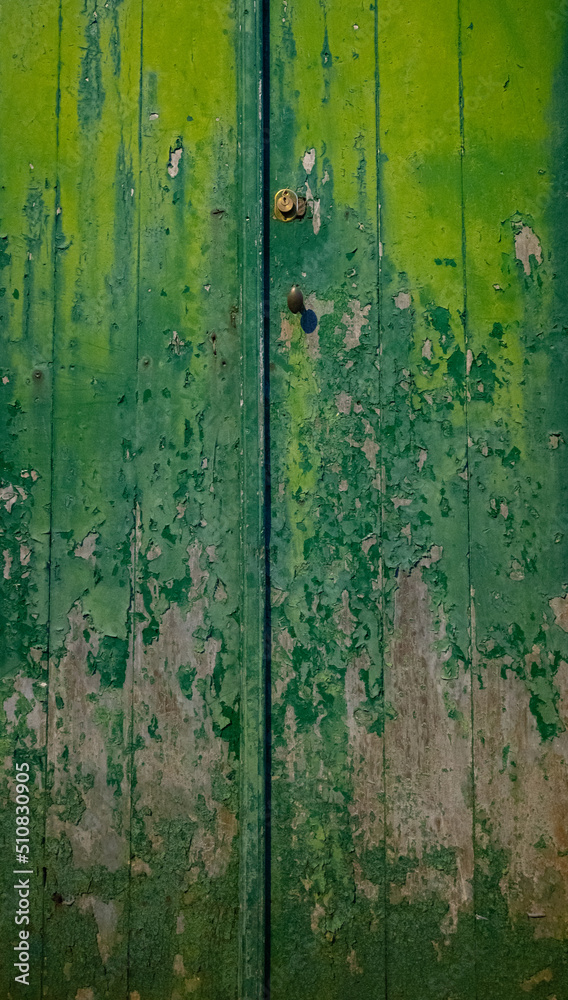 old weathered green wooden doors paint peeling and fading exterior doors of old house in the Azores of Portugal on the island of faial vertical format background or backdrop room for type content 