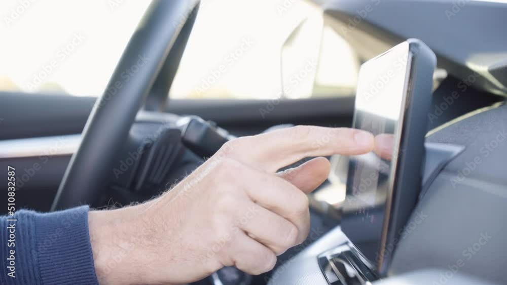 A man works on the touchscreen system on the dashboard in a car - side closeup A man works on the touchscreen system on the dashboard in a car - side closeup