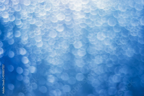 Blue bokeh background with blur white circles, lights. Abstract defocus art background. Out of focus image.