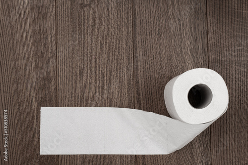 a roll of toilet paper on a wooden background is unwound with a place for an inscription or text copy space