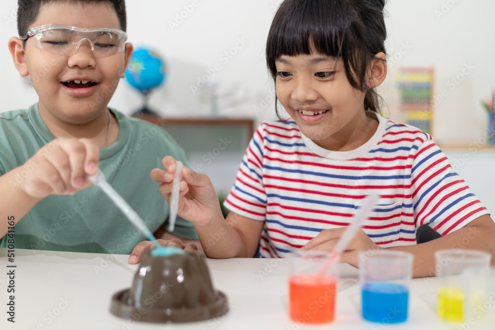 Kids repeating and observing a science lab project at home - the baking soda and vinegar volcano Kids repeating and observing a science lab project at home - the baking soda and vinegar volcano