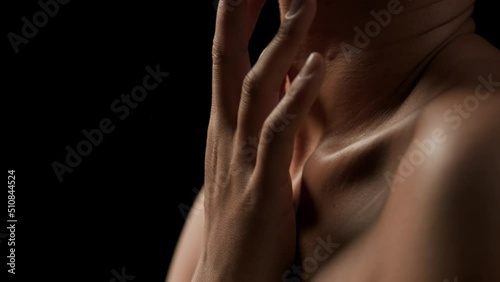 Big close-up shot of gorgeous fit African American woman moves her head up and strokes her clavicle on black background | Wrinkles prevention concept photo