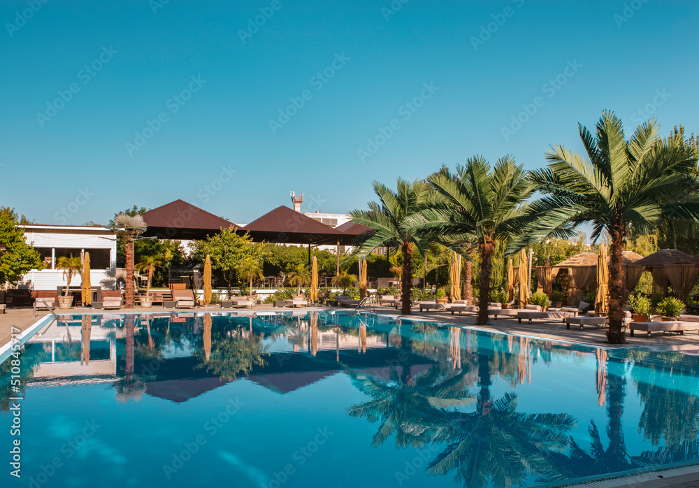 Hotel pool with sunbeds and palm trees at a tropical resort. Swimming pool at the luxury tropical resort
