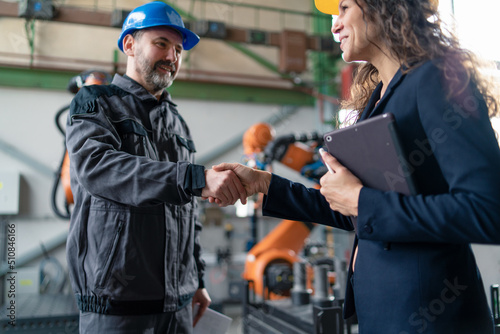 Female engineering manager and mechanic worker fist bumping in industrial factory