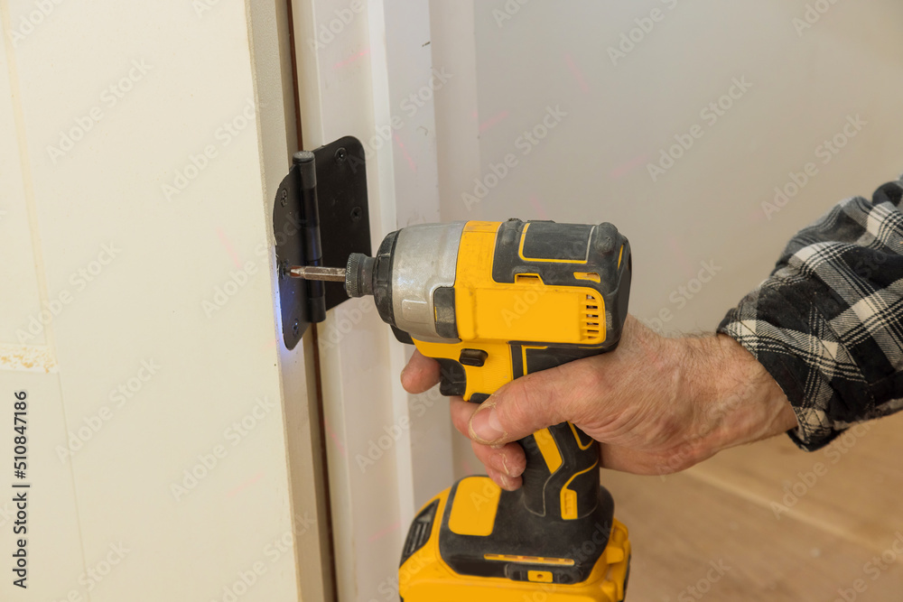 Process of installation stainless door hinges on a white wood door with screwdriver Process of installation stainless door hinges on a white wood door with screwdriver