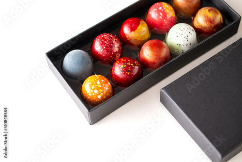 Open gift box with assortment of homemade chocolate bonbons. Modern hand painted chocolate candy. Product concept for chocolatier