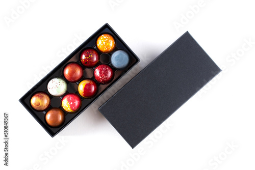 Open gift box with assortment of homemade chocolate bonbons. Modern hand painted chocolate candy. Product concept for chocolatier