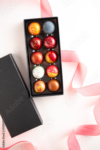 Open gift box with assortment of homemade chocolate bonbons. Modern hand painted chocolate candy. Product concept for chocolatier