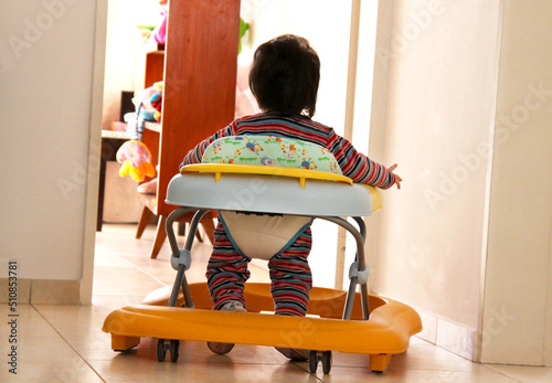 Baby walker. Roller walker training car. 
Baby learning to walk in infant walker. Learning. Baby walker with wheels and safety measures.  
Little girl. Discovery.   photo