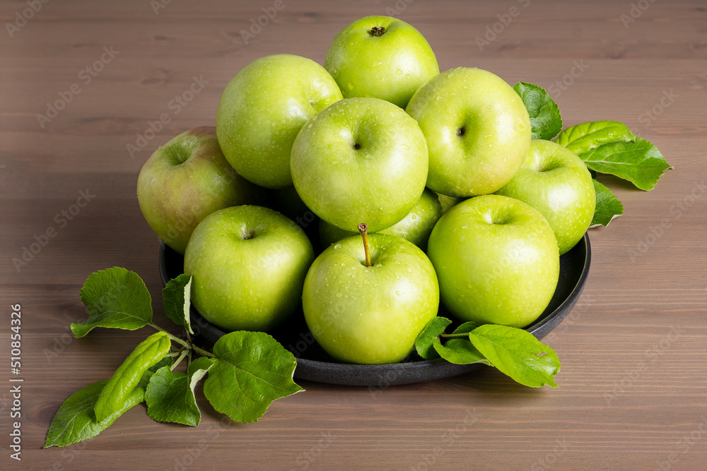 Top view of a composition of fresh ripe green apples and apple tree leaves on a plate wooden background. Selective focus. Top view of a composition of fresh ripe green apples and apple tree leaves on a plate wooden background. Selective focus.
