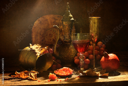 Still life with kumgan, wine and pomegranate on a wooden background photo