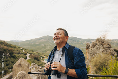 Happy senior man looking at the view from a hilltop