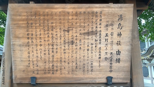 Wooden sign at front of “Yushima Tenjin”, the ancient historic shrine established all the way in year 458, it is written in Japanese characters the origin of its establishment.  Shot taken 2022/6/14 photo