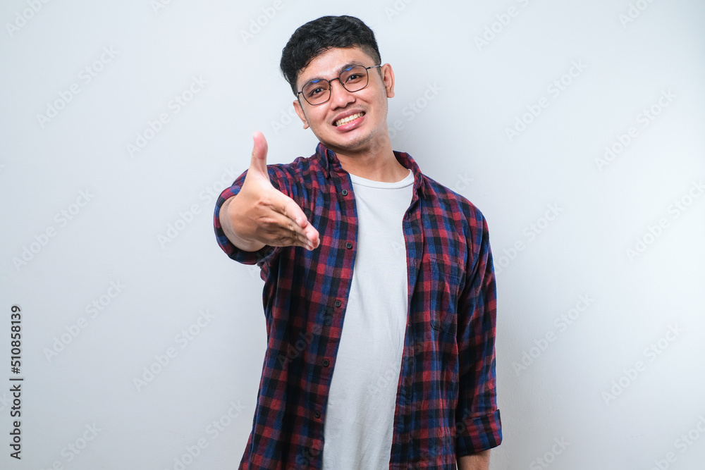 Asian young man smiling friendly offering handshake as greeting and welcoming. successful business. Asian young man smiling friendly offering handshake as greeting and welcoming. successful business.