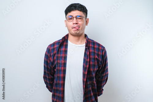 Young handsome asian boy sticking tongue out happy with funny expression. Emotion concept.