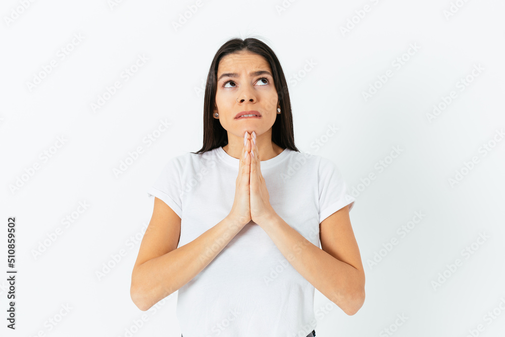 Prayer and begging concept. Young woman wearing a white T-shirt Prayer and begging concept. Young woman wearing a white T-shirt