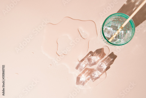 Melting ice cubes with water glas. Cold refreshment in the summer. Concept for hydration in the summer. Background with top down view of cold beverage and copy space.