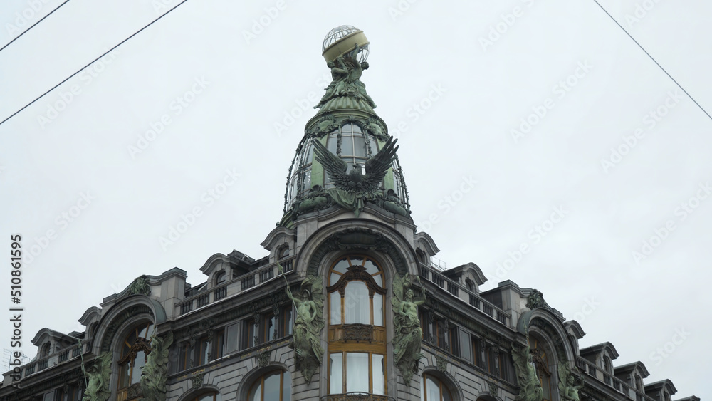 Fototapeta premium Singer house in Saint Petersburg. Action. Bottom view on details of architecture of tower of old house. Beautiful green statues and glass dome of old building in modernist style on background of