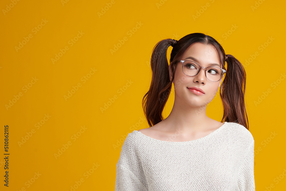 Curious Asian girl is thinking and standing on yellow background with curious face, blank copy space for your advertising content. Curious Asian girl is thinking and standing on yellow background with curious face, blank copy space for your advertising content.