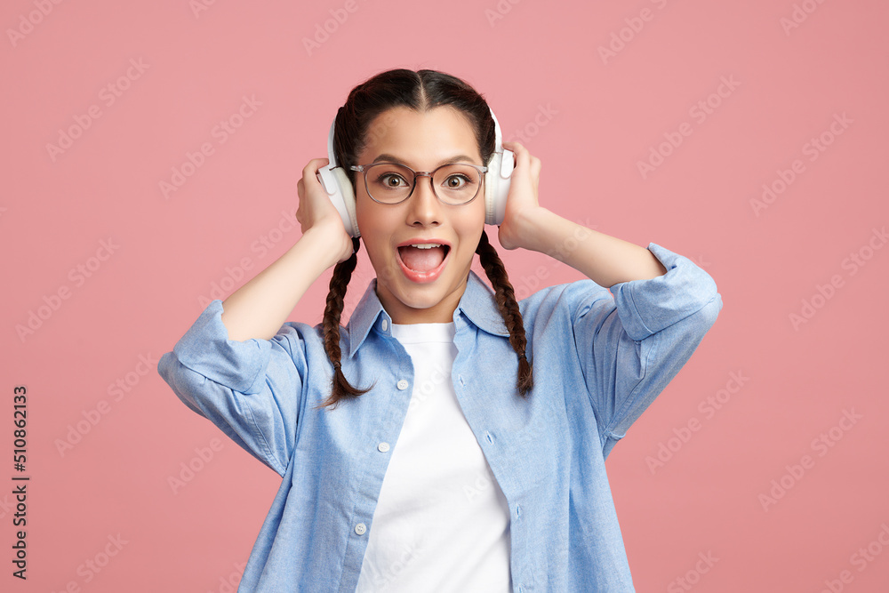 Cute Asian girl is wearing headphone and standing on pink background with happy face, blank copy space for your advertising content. Cute Asian girl is wearing headphone and standing on pink background with happy face, blank copy space for your advertising content.