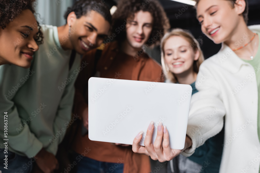 selective focus of digital tablet in hand of woman near multiethnic students smiling on blurred background. selective focus of digital tablet in hand of woman near multiethnic students smiling on blurred background.